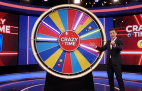 Crazy Time Live Casino Show von Evolution Gaming mit Riesenrad, bunten Segmenten und begeistertem Spielshow-Moderator